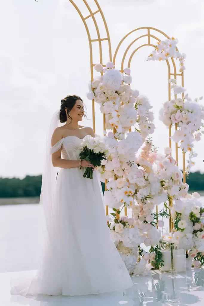 Braut steht vor opulent geschmücktem Traubogen mit Blumen bei einer freien Trauung